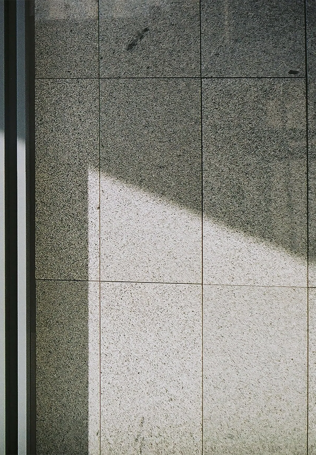 Grey stone slabs with fine joints, half in sunlight and half in shade